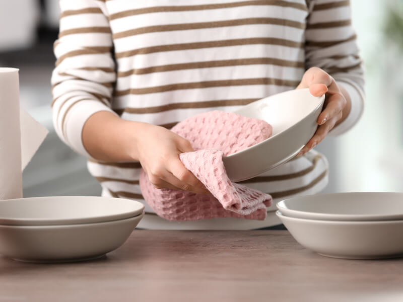 キッチンタオルで食器を拭いている女性